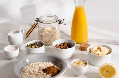 Delicious breakfast ingredients featuring oats, nuts, and fresh orange juice on a bright surface.
