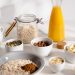 Delicious breakfast ingredients featuring oats, nuts, and fresh orange juice on a bright surface.